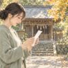 神社の境内でおみくじを読む女性と、専用の結び所を描いた水彩イラスト